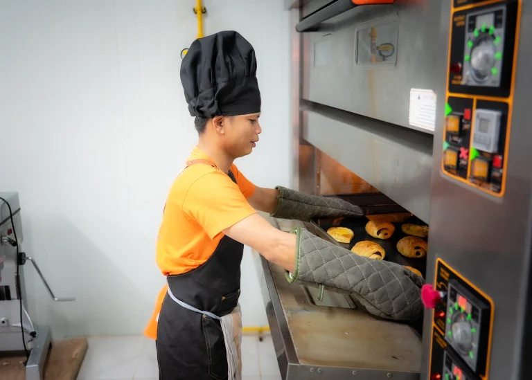 Student with visual impairment baking croissants during hands-on bakery training at the DYP Learning Center in Cambodia