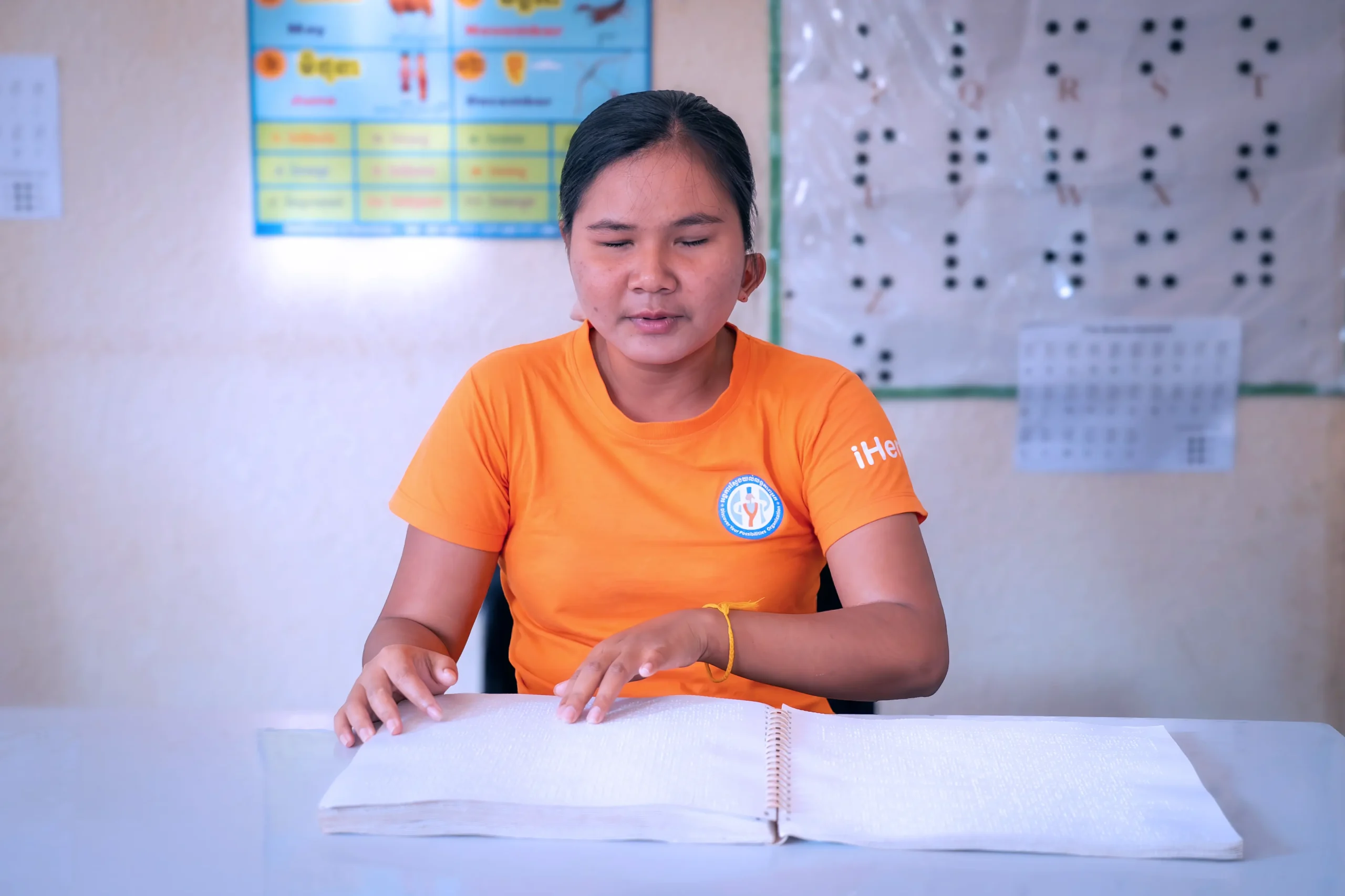 Student reading a Braille textbook at DYP Learning Center, highlighting literacy challenges faced by learners with visual impairments in Cambodia