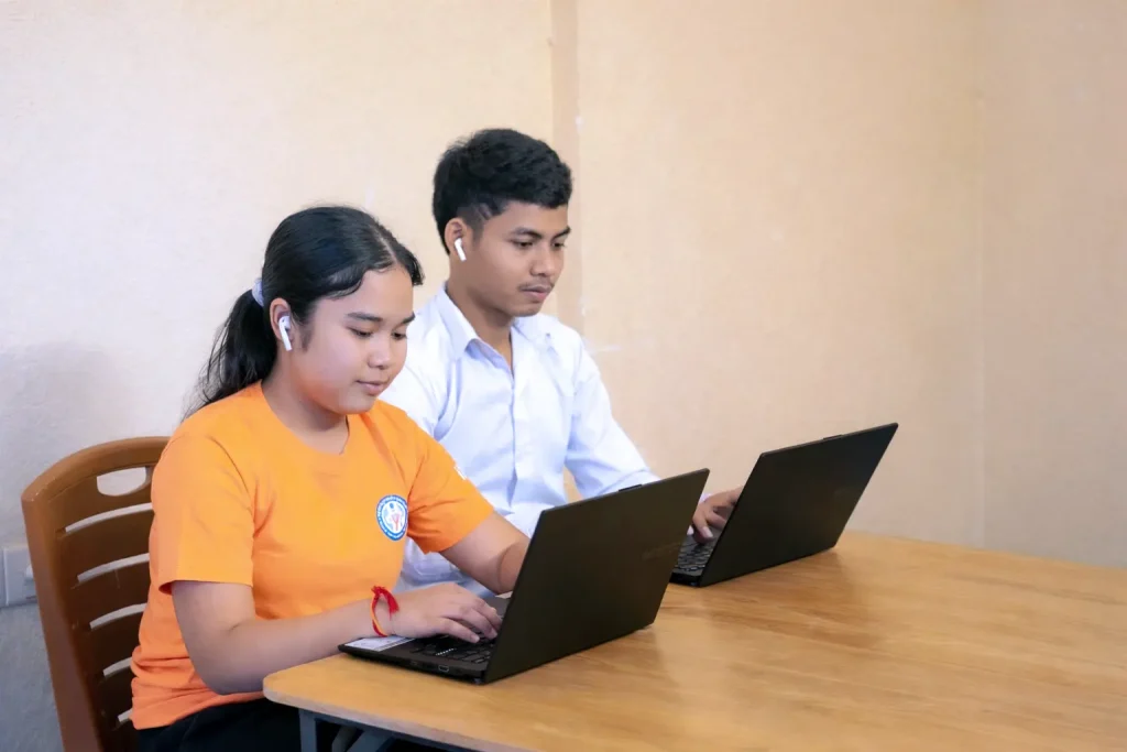 Students with visual impairments using laptops and assistive technology for university study in Cambodia.