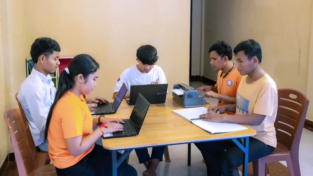 University students with visual impairments studying together using laptops and braille at the DYP Learning Center.