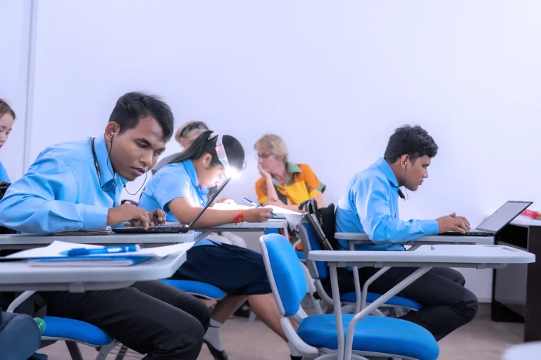 Students with visual impairments using laptops and assistive technology during higher education studies in Cambodia.
