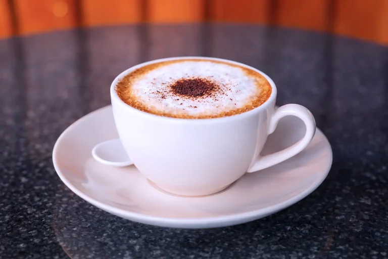 Hot cappuccino with milk foam served in a white cup at the DYP Inclusive Café in Siem Reap.