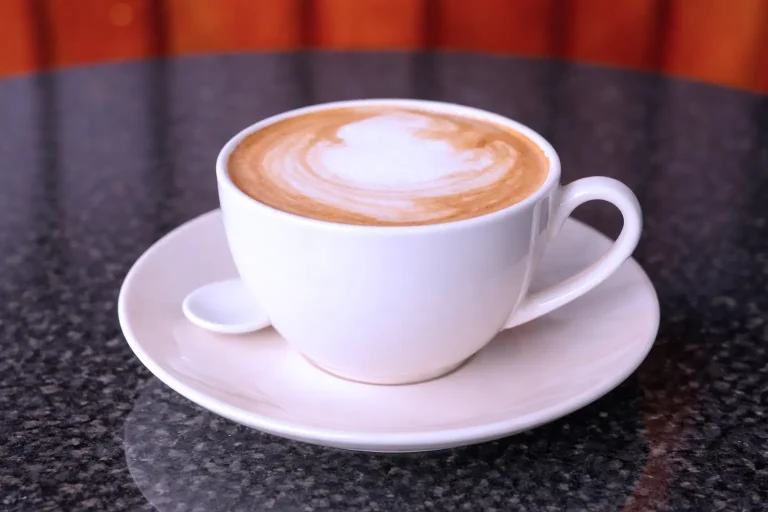 Hot latte coffee with milk foam served in a white cup at the DYP Inclusive Café in Siem Reap.