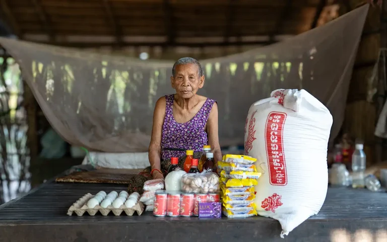 Visually impaired beneficiary with food package support including rice eggs and essential supplies in Cambodia