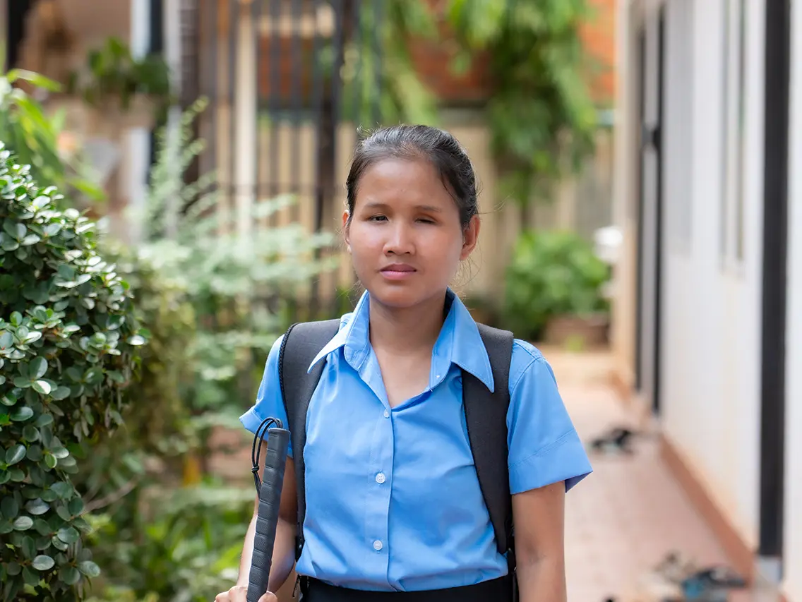 Sreynoy carrying a white cane and school backpack at DYP Cambodia